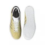 Championes adidas modelo Gazelle, confeccionados en gamuza color amarillo con las icónicas tres tiras laterales en color marrón. Presentan suela de goma blanca, lengüeta blanca y detalle en el talón en color marrón oscuro.