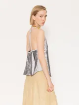 Top corto dorado con breteles finos y espalda cruzada con flecos.