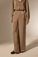 Pantalon de vestir de corte ancho y tiro alto, confeccionado en tela de viscosa con acabado satinado. Presenta cintura elástica y diseño fluido.