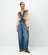 Pantalón de jean corte barrel, de tiro medio y piernas amplias con ruedo ligeramente ajustado. Cuenta con bolsillos funcionales, trabillas para cinturón y cierre frontal con botón y cremallera.