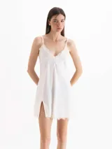 Vestido corto blanco de tirantes finos, con escote en V y detalles de encaje en el escote y el ruedo, con tajo lateral.