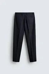 Pantalón de corte recto confeccionado en tejido con lana, color beige. Presenta bolsillos frontales, bolsillos traseros de vivo y cierre frontal con cremallera y botón.