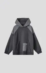 Hoodie oversize de algodón con diseño bicolor en gris oscuro y gris medio. Presenta capucha forrada, mangas raglán con recortes técnicos y un bolsillo frontal tipo canguro con un compartimento adicional con solapa.