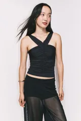 Top negro de punto elástico con breteles anchos que se cruzan en la espalda. Diseño ceñido con frunces en la parte delantera que crean un efecto drapeado.