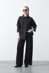 Jean wide leg de color negro con silueta amplia y caída fluida. Presenta detalles de tachas aplicadas que recorren el diseño en forma de ondas. Confeccionado en denim de algodón.