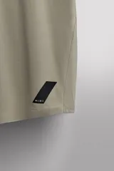 Camiseta de entrenamiento regular fit color beige, confeccionada en combinación de tejidos técnicos ligeros y elásticos con tecnología Quick Dry nivel 2. Presenta cuello redondo, manga corta, acabados con costuras planas y termofijadas, y detalle de logo estampado en el bajo.