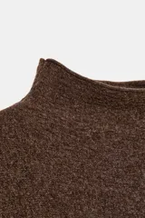 Jersey de punto color marrón con cuello subido y manga larga. Presenta un diseño de cuerpo amplio estilo capa con sisa ancha y bajo asimétrico con aberturas laterales.