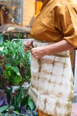 Delantal corto de algodón color crudo con teñido artesanal shibori en tonos marrones.