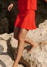 Minifalda roja de lino y rayón, de tiro medio, corte recto y tablas laterales.