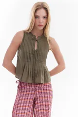 Blusa blanca sin mangas de algodón, con diseño de tablas frontales y escote con lazos para atar.