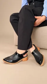 Zapatos destalonados de cuero color tostado, con perforaciones en el empeine y cierre lateral con hebilla metálica.