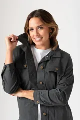 Campera de estilo camisa oversize en color gris oscuro, confeccionada en tejido de algodón con elastano. Presenta cuello clásico, cierre frontal con botones, bolsillos frontales con solapa en el pecho y bolsillos laterales tipo parche. Posee mangas largas con puños abotonados y un corte holgado ideal para media estación.