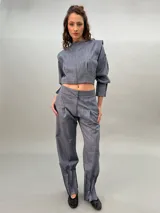 Pantalón de vestir gris con bolsillos laterales, pretina a la cintura y tablas en los bajos.