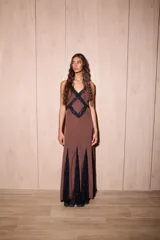 Vestido largo de seda color marrón con estampado de lunares blancos y detalles de encaje negro. Presenta un diseño entallado en el torso, escote en V profundo y espalda descubierta con tiras cruzadas.