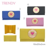 Billetera azul con cierre de solapa y broche a presión. Tiene un aplique circular con borde dorado y la inscripción "Self Love Club Trendy" con un corazón rosa en el centro.