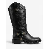 Bota de caña alta estilo western, confeccionada en cuero negro. Presenta un diseño con costuras decorativas, tiradores laterales con remaches metálicos y una correa ajustable con argolla y remaches en la zona del tobillo.