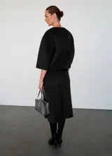 Falda midi recta de tiro medio, confeccionada en mezcla de lana con forro interior y abertura posterior en el bajo.