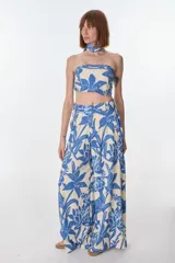 Pantalón ancho de tiro alto, color beige con estampado floral en azul. Presenta pliegues en la cintura y lazo para ajustar.