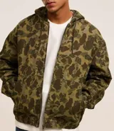 Campera con capucha y cierre frontal, confeccionada en sarga con estampado camuflado. Tiene manga larga con sisa desplazada, puños ajustados, bolsillo canguro y bajo con elástico.