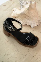 Sandalias de cuero color beige con plataforma y taco cuadrado de madera. Presentan una tira frontal ancha y una tira ajustable en el tobillo con hebilla metálica plateada.