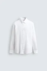 Camisa blanca de lino de corte regular fit, con cuello abotonado, manga larga y cierre frontal de botones.
