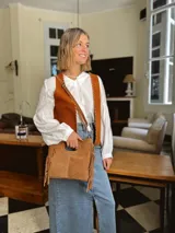 Cartera bandolera de cuero color camel, con forro interno de tela y flecos laterales.