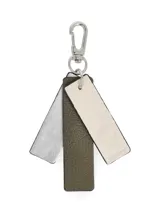 Llavero con mosquetón metálico plateado y tres tiras colgantes de cuero sintético en color crudo, verde militar y plateado texturizado.