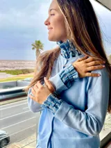 Conjunto de cuello y puños desmontables de lino celeste con bordados florales en blanco y celeste. El cuello es tipo babero con volados y los puños tienen elástico.