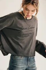 Remera de manga larga gris oscuro con efecto lavado gastado, corte oversize y cuello redondo amplio. Cuenta con estampado tipográfico manuscrito en el pecho.