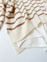 Sweater tejido color crema con rayas horizontales marrones, cuello redondo y corte holgado.