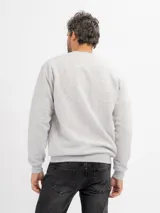 Buzo de felpa color beige, de cuello redondo y mangas largas con puños acanalados.