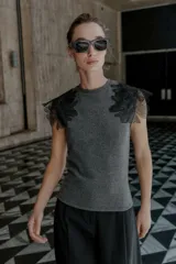Top gris de cuello redondo y sin mangas, con detalle de flores negras de organza en los hombros.