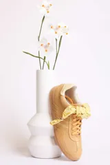 Zapatillas bajas color marrón con cordones y charms dorados.