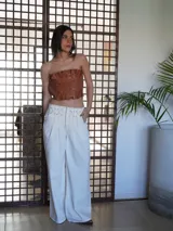 Pantalón wide leg de tiro medio confeccionado en denim, con cintura trabajada con pasacintas entrelazadas, cierre frontal y bolsillos laterales.