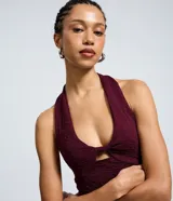 Vestido midi color bordó con textura, cuello halter y detalle de nudo con abertura en el busto.