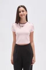 Remera cropped de color rosado con cuello redondo y detalles de costuras en color marrón. Presenta un bordado frontal con el número 94 y estrellas.