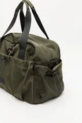 Bolso de nylon en color verde militar, con diseño deportivo, asas de mano resistentes, cierre superior y bolsillos laterales con frunce ajustable mediante cordón elástico.