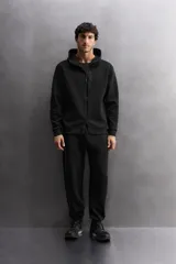 Pantalón jogger de entrenamiento, corte regular fit, color verde oliva oscuro. Confeccionado en tejido técnico compacto de algodón con elasticidad y efecto neopreno. Presenta cintura elástica ajustable con cordón blanco, bolsillos frontales y un bolsillo lateral con cierre de cremallera. El bajo termina en puño.