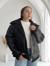 Campera negra de cuero sintético con interior de piel sintética color negro, corte oversize, cuello solapa y cierre frontal con cremallera.