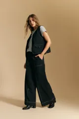 Pantalón largo color crema, tiro alto, de corte recto y ancho. Presenta costuras visibles en contraste y bolsillos delanteros.