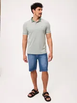 Remera polo de piqué de algodón melange color celeste, con cuello y puños en contraste blanco y azul, cierre frontal con botones y bordado pequeño en el pecho.