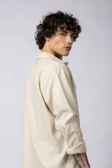 Camisa de manga larga confeccionada en lino, color verde oliva, con cuello clásico y cierre frontal de botones.