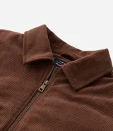 Campera bomber de pana color marrón, con cuello polo, cierre frontal con cremallera y puños y bajo elásticos.