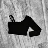 Top corto asimétrico de color gris oscuro, con un hombro descubierto, manga larga y tirantes finos en el hombro opuesto.