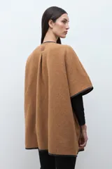 Capa color tostado con vivos en contraste de color negro, cierre frontal con un botón grande y un bolsillo lateral.