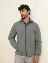 Campera impermeable gris con capucha, cierre frontal y bolsillos laterales con cremallera.