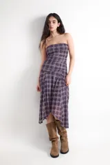 Vestido midi de palabra de honor con estampado de cuadros en tonos morados y beige. Presenta fruncidos en los laterales y un bajo asimétrico.