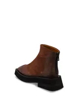 Bota de cuero negra con caña baja, punta cuadrada y suela track.