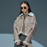 Campera de estilo aviador en color taupe, confeccionada en material símil gamuzado con interior y detalles de bordes en corderito sintético color crema. Presenta cierre frontal, dos bolsillos frontales con solapa y botones metálicos, y cuello solapa.