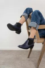 Botín negro de cuero con elásticos laterales, taco bajo y tirador trasero.